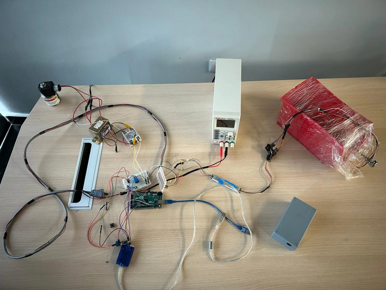 Bench test rig: an Arduino Mega with breadboard and DB9 serial links wired to a bench power supply, a solenoid valve, a solid-state relay and the CAN-connected motor driver.